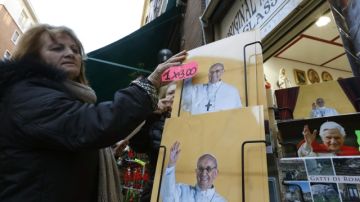 Una mujer mira en  Roma afiches con  con la imagen del Papa, Francisco, cuya entronización tendrá lugar el próximo martes.