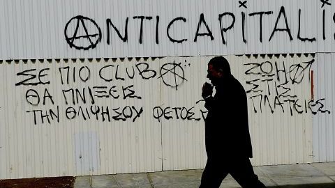 Un hombre camina junto a un mensaje anticapitalista en el centro de Nicosia en Chipre hoy, 19 de marzo de 2013.