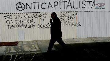 Un hombre camina junto a un mensaje anticapitalista en el centro de Nicosia en Chipre hoy, 19 de marzo de 2013.