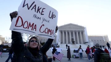 Una partidaria de los matrimonios de personas del mismo sexo, Carolyn Marosy, sostiene un cartel en el que se lee "¡Despertad de vuestro DOMA coma!"), " ante el Tribunal Supremo de Estados Unidos en Washington DC.