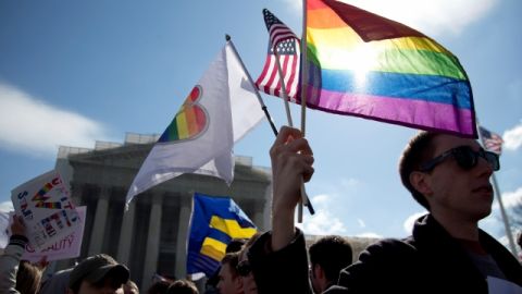 Kevin Coyne of Washington holds flags in front of the Supreme Court in Washington, Wednesday, March 27, 2013. The U.S. Supreme Court, in the second day of gay marriage cases, turned Wednesday to a constitutional challenge to the federal law that prevents legally married gay Americans from collecting federal benefits generally available to straight married couples.  (AP Photo/Carolyn Kaster)