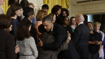 El presidente Barack Obama (i) y el vicepresidente Joe Biden (d) abrazan a varias personas afectadas por tiroteos.