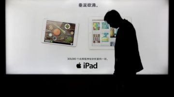 Un hombre camina delante de un anuncio que muestra un iPad en Shanghai, China.
