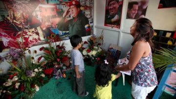 Una mujer y sus dos hijos visitan la capilla en la que se rinde culto a Chávez en el barrio 23 de Enero, Caracas.