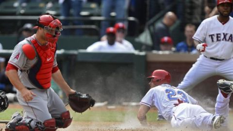 El receptor de Angels Chris Iannetta (i) pierde el control de la pelota en la octava entrada, y permite la carrera de la victoria de los Rangers de Texas a Graig Gentry (d).
