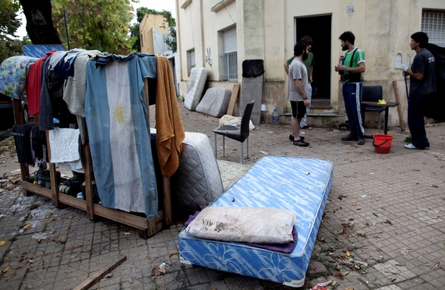 Varios  hombres están fuera de sus hogares con sus pertenencias  después de las inundaciones en La Plata que han dejado hasta el momento decenas de muertos.
