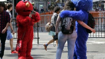 Un personaje de Elmo utiliza una cámara de una cliente para fotografiarla con un compañero que interpreta a “Cookie Monster” en la zona de Times Square.