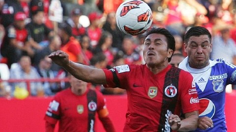 El jugador del Xolos, Noé Maya (izq.), disputa el balón con José Tancredi,  del Millonarios, en la cancha del Estadio Caliente.