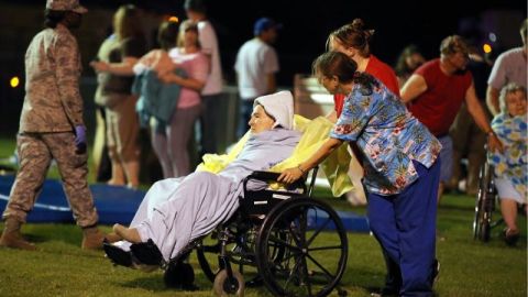 Varias personas asisten a anciana evacuada al campo deportivo de una escuela local en West, TExas, luego de la explosión e incendio en una fábrica de fertilizantes en Waco.