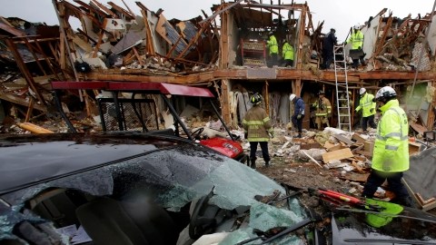 Un coche severamente dañado se observa enfrente de un edifico de departamentos totalmente destruído como resultado de la explosión mientras  rescatistas inspeccionan el lugar en West, Texas.