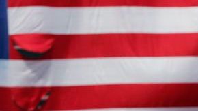 Voluntarios del Maratón de Boston sostienen la bandera mientras David Ortiz le habla ala gente en Fenway.