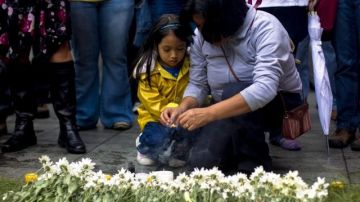 Una mujer coloca flores junto a su hija en una protesta de víctimas de la represión militar frente a la Corte para exigir la continuación dell juicio por genocidio en contra del exdictador José Efraín Ríos Montt.