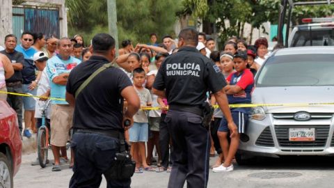 Policías aseguran el lugar donde encontraron los cadáveres de cinco hombres y dos mujeres en el interior de una casa en un barrio de bajos ingresos en la ciudad turística de Cancún, México, el domingo 14 de abril 2013.
