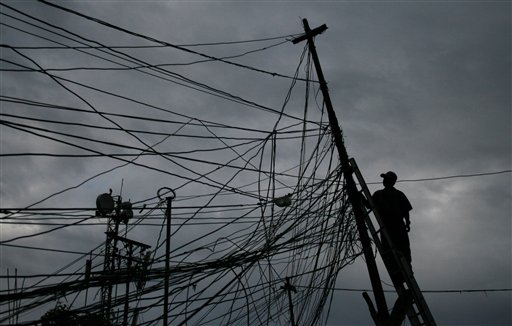 Un miembro de una compañía eléctrica quita todos los cables instalados ilegalmente en un barrio de Caracas.