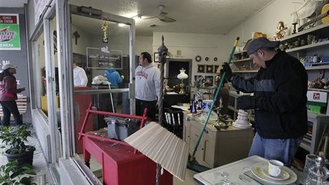 Bobby Rios (d) recoge cristales de las vidrieras en una tienda en West, Texas, que se dañaron con la explosión ocurrida en la planta de fertilizantes.