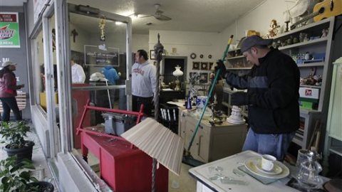 Bobby Rios (d) recoge cristales de las vidrieras en una tienda en West, Texas, que se dañaron con la explosión ocurrida en la planta de fertilizantes.