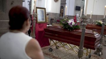 Una mujer observa los féretros que contienen los restos del obispo guatemalteco Juan José Gerardi (abajo), asesinado en 1998.