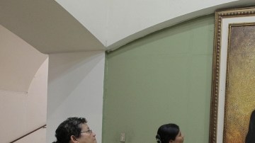 Salvadoreñas observan pintura del arzobispo asesinado de San Salvador Óscar Arnulfo Romero.