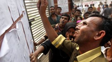 Bangladeshíes buscan a sus familiares en la lista de víctimas del derrumbe.