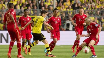 Robert Lewandowski, del Dortmund, intenta llevarse el balón ante un muro de piernas del campeón alemán, Bayern Munich.