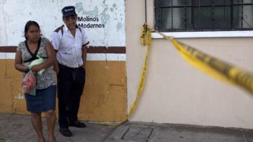 Dos personas observan el lugar donde fue hallada una bolsa negra que contenía la cabeza de una mujer en la población de San Rafael Las Flores.