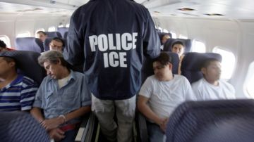 Un agente de la Oficina de Inmigración y Aduanas (ICE) camina por un avión especial con inmigrantes rumbo a su deportación.