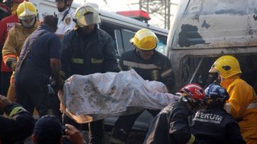 Bomberos remueven el cuerpo de un hombre que resultó herido durante la explosión de un camión que transportaba gas.