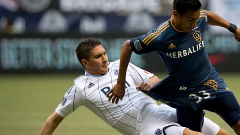 Vancouver Whitecaps' Johnny Leveron, left, of Honduras, takes down Los Angeles Galaxy's Jose Villarreal   in Vancouver, British Columbia.