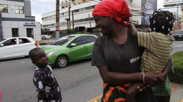 Una mujer camina cerca de uno de los niños haitianos que mendigan en las calles de Santo Domingo.