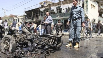 Policías afganos inspeccionan el escenario de un ataque con un auto bomba.