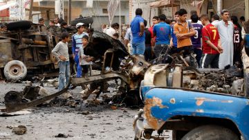 Curiosos inspeccionan uno de los carros bomba que explotaron este lunes en Bagdad.
