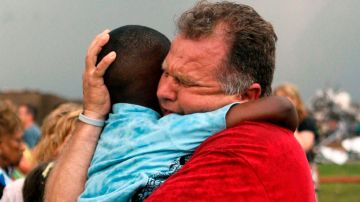 Un hombre abraza a uno de los niños que fueron rescatados vivos debajo de los escombros de la escuela en Moore.