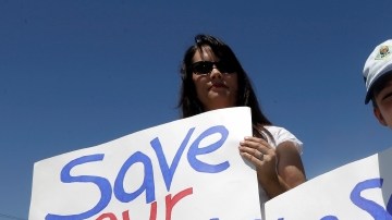 Terri Hall, izq, de San Antonio, Texas, junto a su hijo  Nathaniel Hall, 8, sostienen carteles en contra de admitir exploradores gay, durante la reunión en Grapevine, Texas.