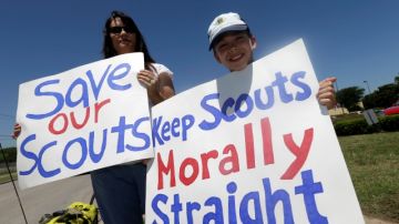 Terri Hall, izq, de San Antonio, Texas, junto a su hijo  Nathaniel Hall, 8, sostienen carteles en contra de admitir exploradores gay, durante la reunión en Grapevine, Texas.