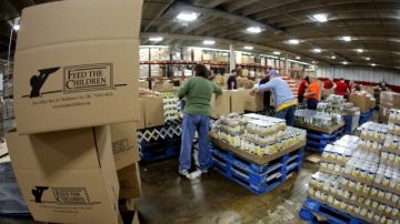 Varios voluntarios llenan cajas con alimentos perecederos en un centro de distribución de Oklahoma.