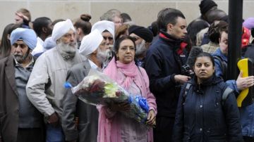 Una mujer lleva flores al lugar donde se produjo el asesinato de un soldado en el barrio de Woolwich, en Londres.
