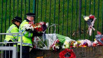 Personas colocan flores en el lugar donde fue asesinado un soldado en el barrio de Woolwich, en Londres.