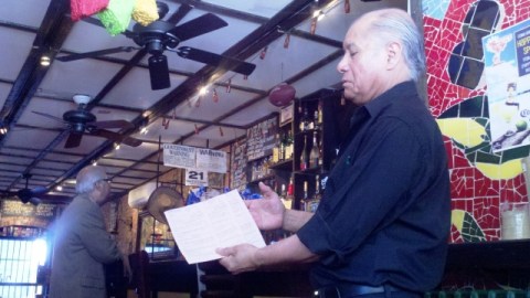 Jorge Villegas, gerente de Mojitos, muestra una de las multas que le dio NYPD al negocio. En el círculo, detalle de una penalidad por no exhibir su certificación.