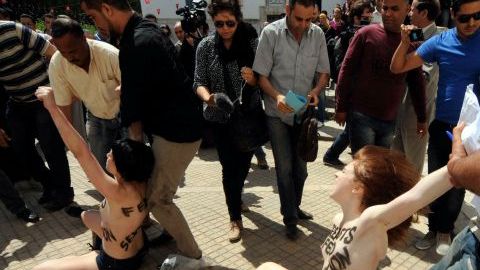 Las jóvenes activistas de Femen, una de Alemania y dos francesas, se acercaron hasta la puerta del ministerio de Justicia usando largos sacos y luego se los quitaron.