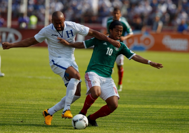 Víctor Bernardez, de la selección de Honduras, intenta controlar la maniobra del  delantero mexicano Gio Dos Santos, en un partido de las eliminatorias.
