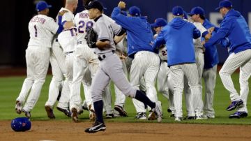 Mientras el jardinero central de los Yankees Ichiro Suzuki sale del terreno de juego, al fondo los jugadores de los Mets festejan uno de los triunfos en Citi Field.