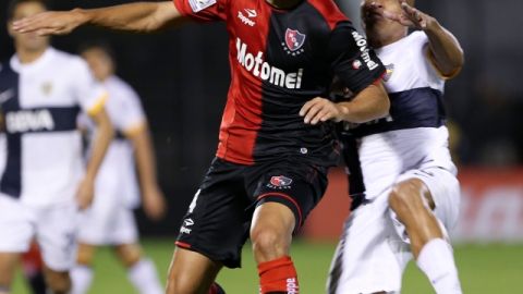 Marcos Caceres, left, vies for the ball with Argentina's Boca Juniors Clemente Rodriguez during a Copa Libertadores soccer match in Rosario, Argentina, Wednesday, May 29, 2013. (AP Photo/Daniel Jayo)