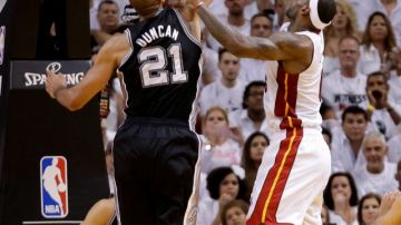 LeBron James (d), la estrella del Miami Heat, trata de encestar ante la defensa de Tim Duncan, el referente de los Spurs de San Antonio, en el primer partido de las finales de la NBA.
