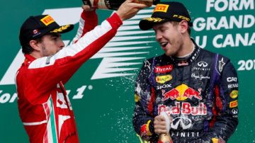El español Fernando Alonso (izq.), quien llegó segundo en el GP de Canadá, baña en champaña al ganador,  el alemán Sebastian Vettel.