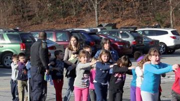 Escolares y maestros huyen de la escuela primaria Sandy Hook, en Newtown, Connecticut, el día en que se reportó la masacre.