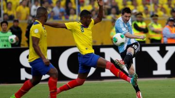 Lionel Messi  realiza un disparo ante Frickson Erazo  y Jorge Guagua, de Ecuador,  en el duelo por las eliminatorias sudamericanas.