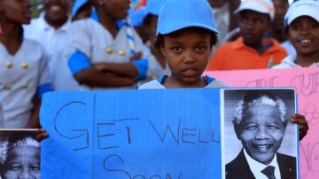 Estudiantes sudafricanos sostienen carteles con mensajes para que el expresidente Nelson Mandela mejore.