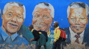 Unos estudiantes caminan frente a un mural del expresidente Nelson Mandela en  Johannesburgo.