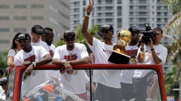 El jugador de los Miami Heat, Chris Bosh, junsto a sus compañeros de equipo, sostiene el trofeo del campeonato de la NBA durante el desfile por las calles de Miami.