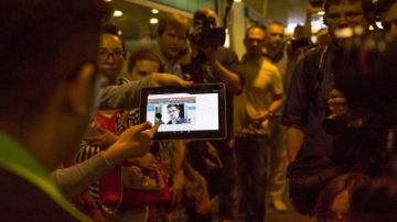 Periodistas muestran los pasajeros procedentes de Hong Kong una tableta con una foto de Edward Snowden, un exempleado de la CIA buscado por EEUU.